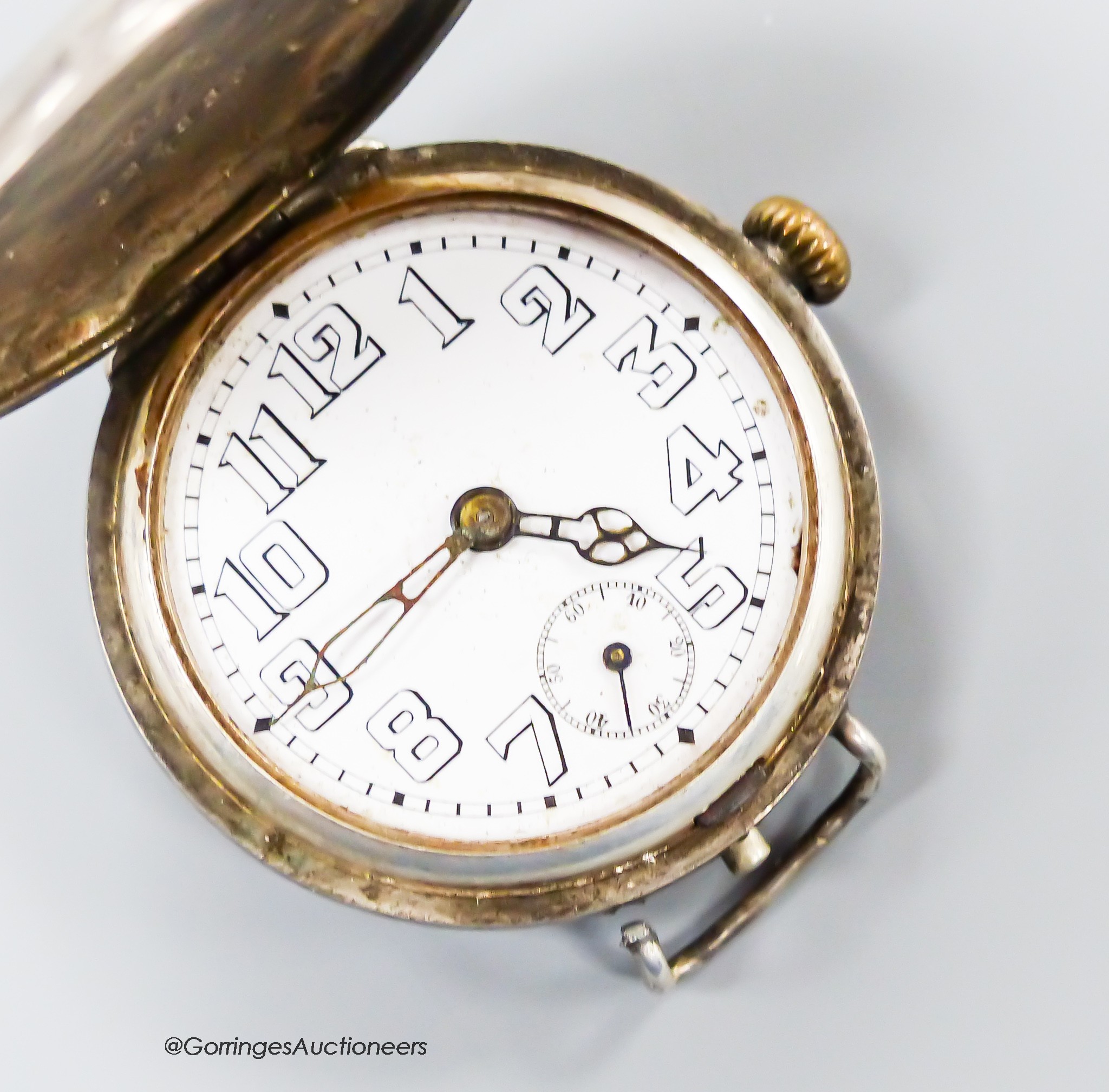 An early 20th century silver Rolex manual wind hunter trench watch with Arabic dial and subsidiary seconds, no strap, part of one lug detached and engraved monogram, case diameter 35mm.